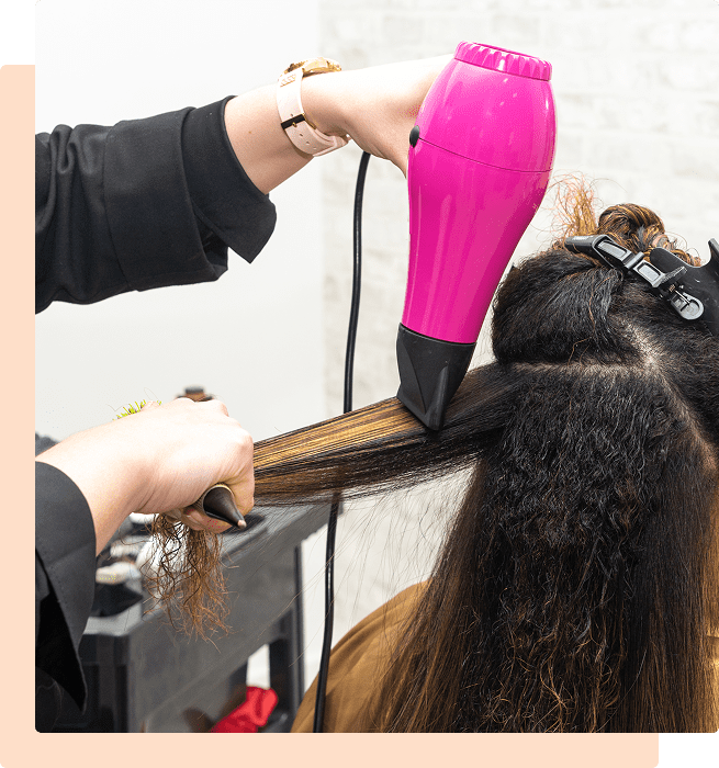Blow-drying hair with a pink tool.