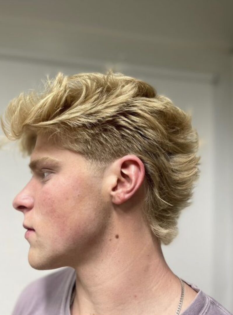 Side profile of a young man with a blonde mullet hairstyle.