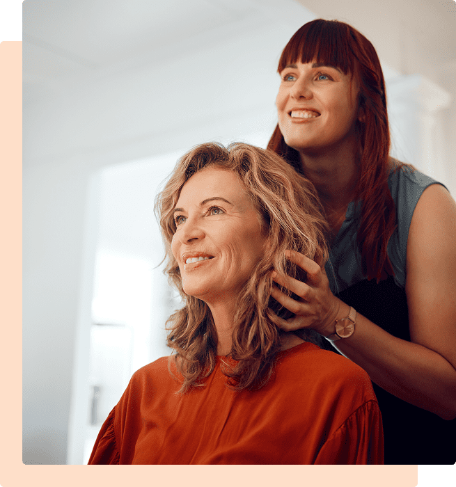 Hairdresser styling a smiling woman's hair in a bright salon.