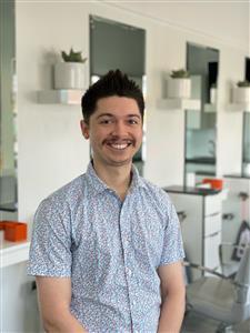 Man with mustache smiling in a modern kitchen.