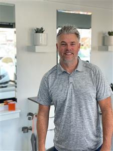 Smiling man in a casual gray polo shirt indoors.