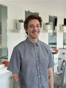 Smiling young man in a casual button-up shirt indoors.