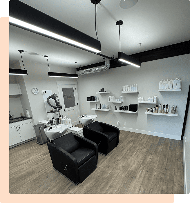 Modern hair salon with black wash stations and white shelves.