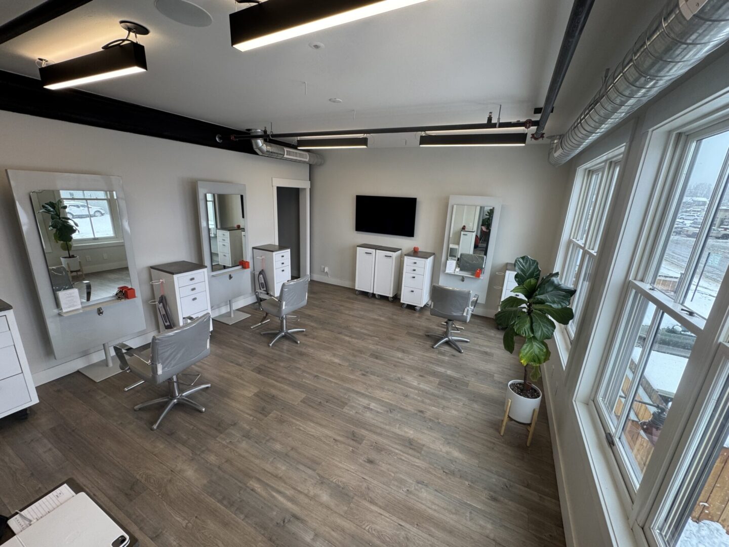 Modern office space with desks, chairs, and a TV screen.